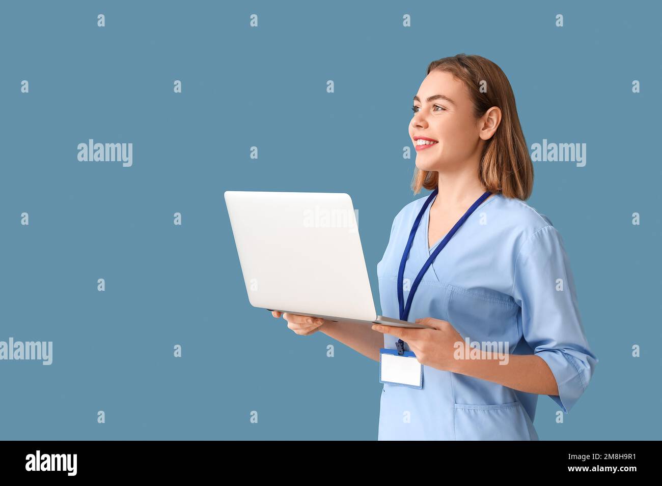 Female intern with laptop on blue background Stock Photo - Alamy