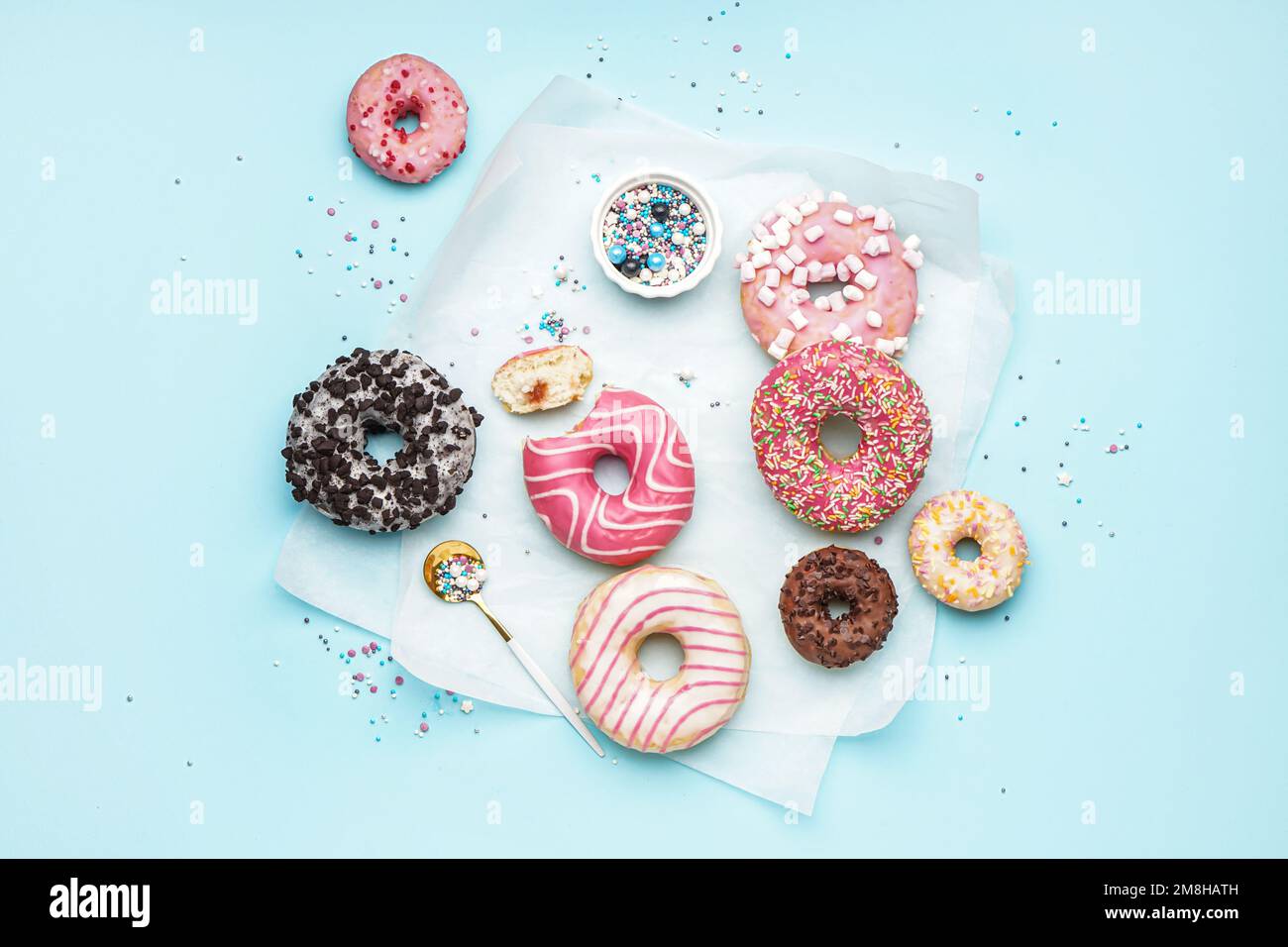 Parchment with different delicious donuts on blue background Stock Photo