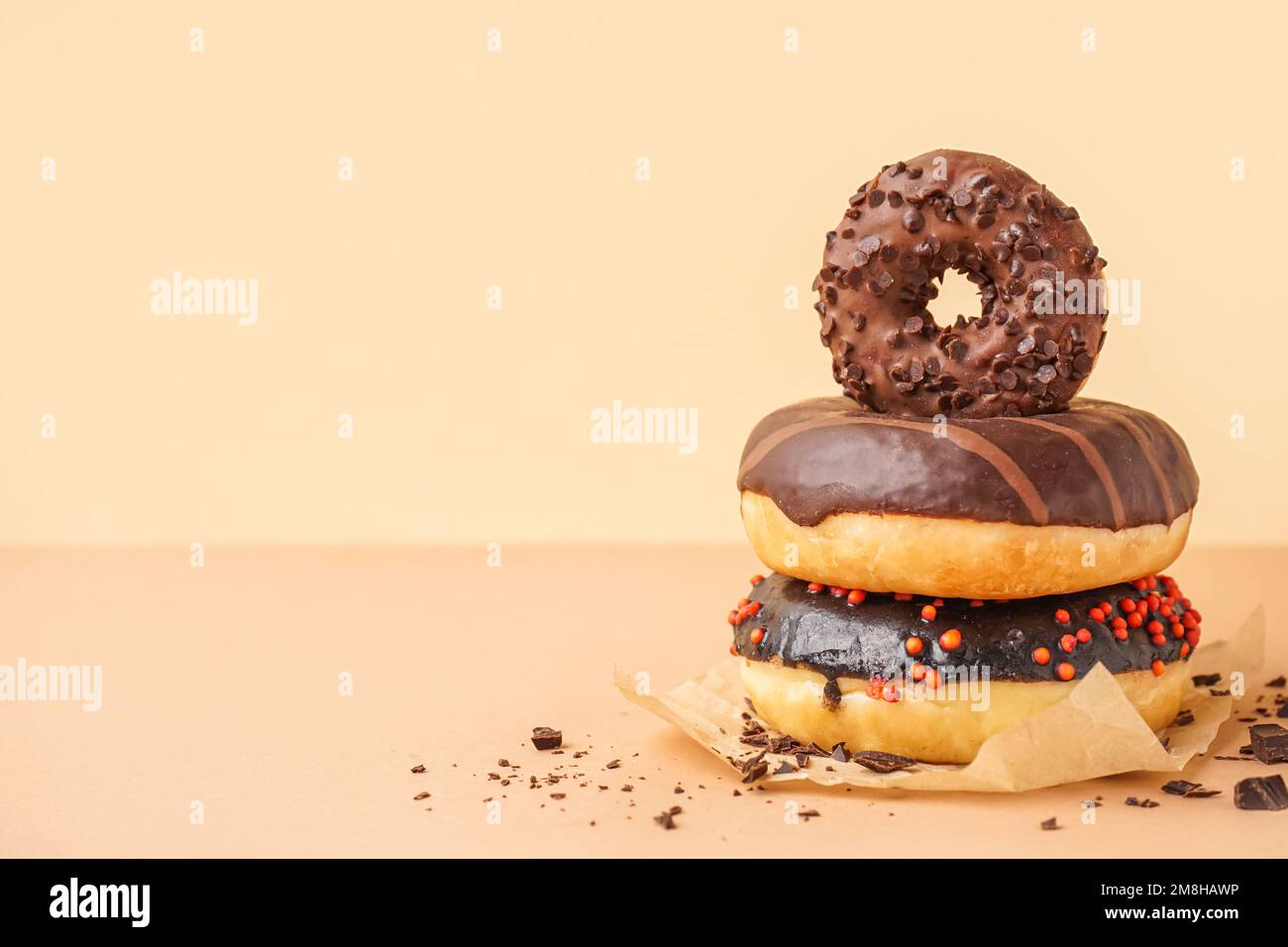 Parchment with delicious chocolate donuts on beige background Stock Photo