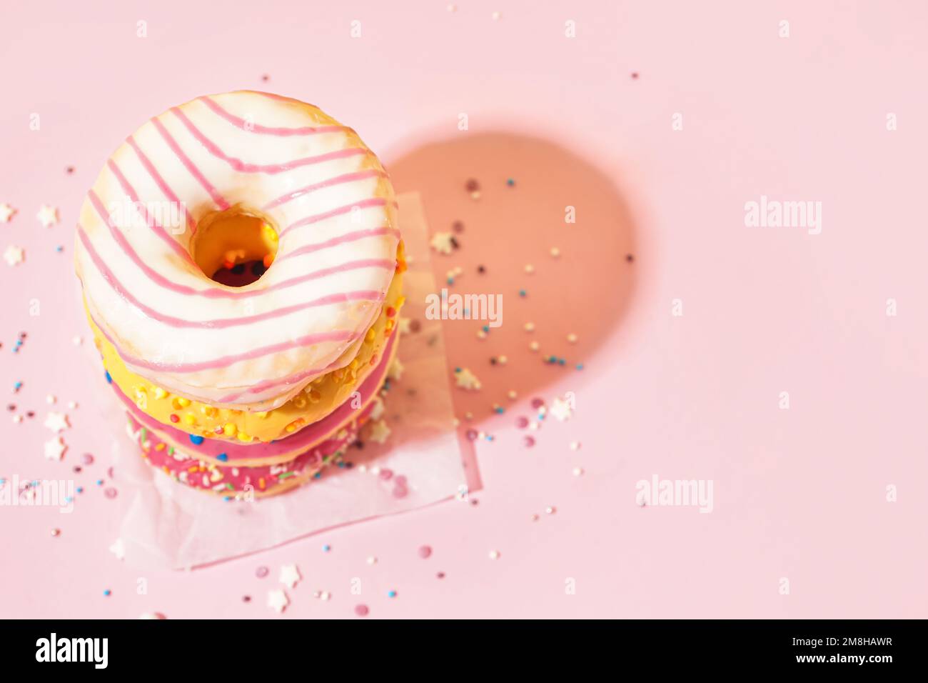 Parchment with different delicious donuts on pink background Stock Photo