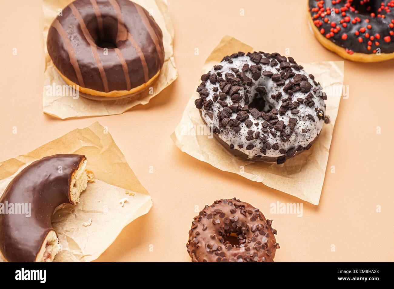 Parchments with different delicious donuts on beige background Stock Photo