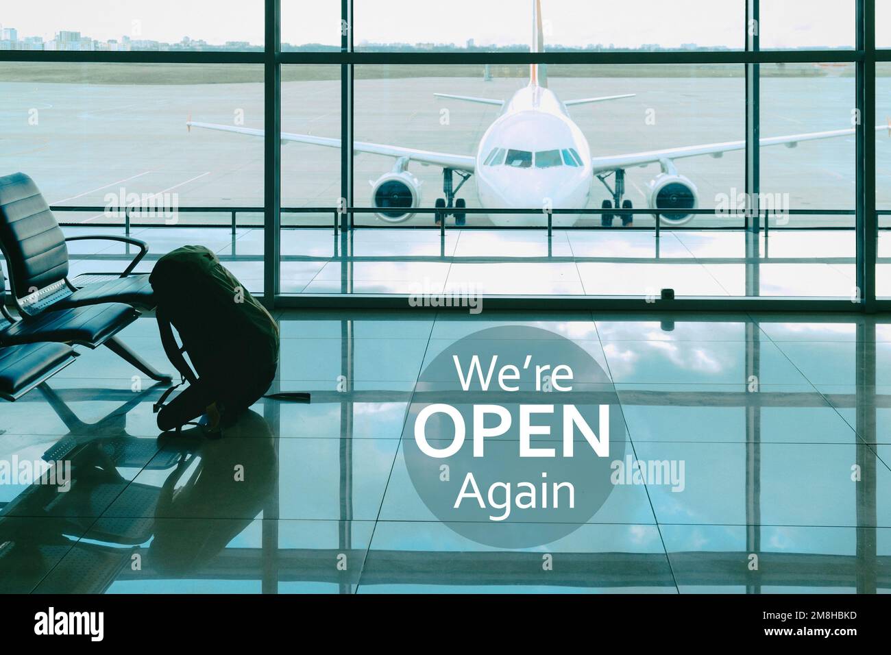 We are open again. Sign at the airport luggage on the chair in waiting lounge luggage waiting for departure. Travel backpack baggage and airplane. Stock Photo