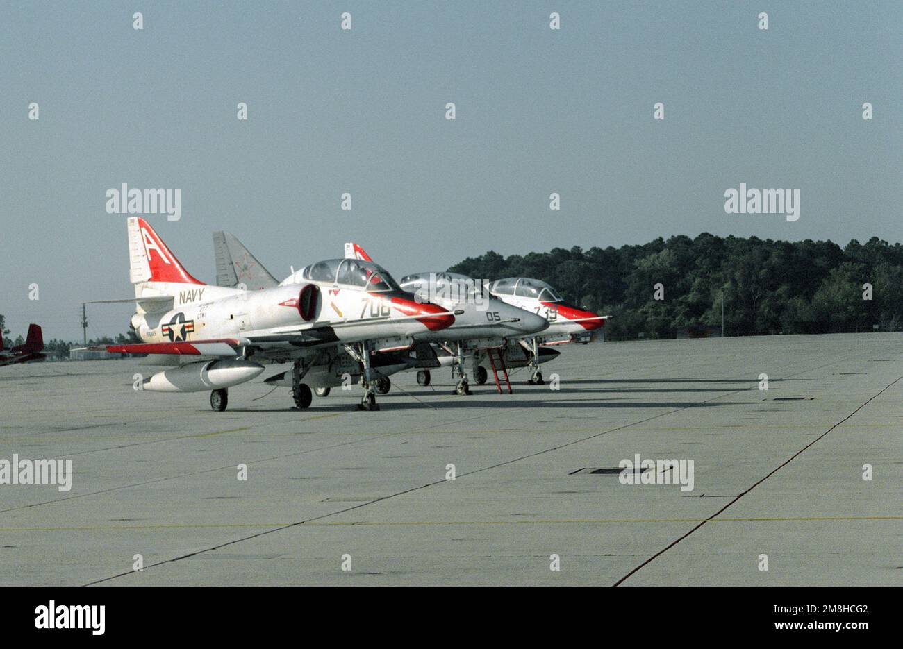 A right side view of two Training Squadron 7f (VT-7) TA-4J Skyhawk aircraft parked on either side of a TA-4F Skyhawk from an aggressor squadron. Base: Naval Air Station, Pensacola State: Florida (FL) Country: United States Of America (USA) Stock Photo