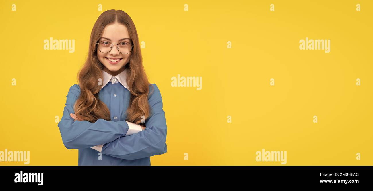 Confident teenage girl in eyeglasses happy smile keeping arms crossed blue background, confidence. Child face, horizontal poster, teenager girl Stock Photo