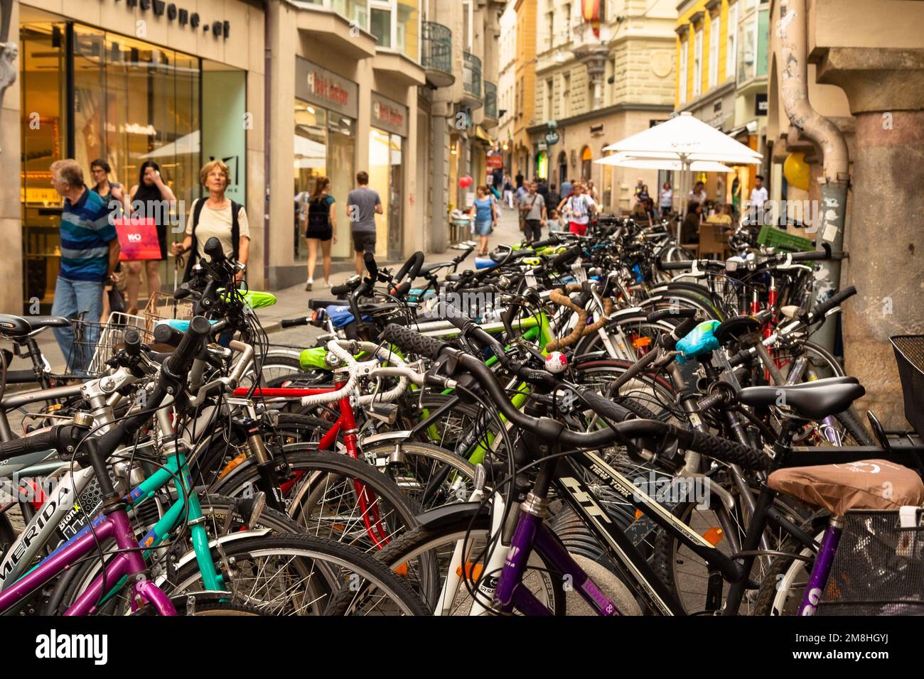 A shopping street with a lot of bicycles lined up as pedestrians walk by, one is wearing a Wookie onesie. Graz, Austria Stock Photo
