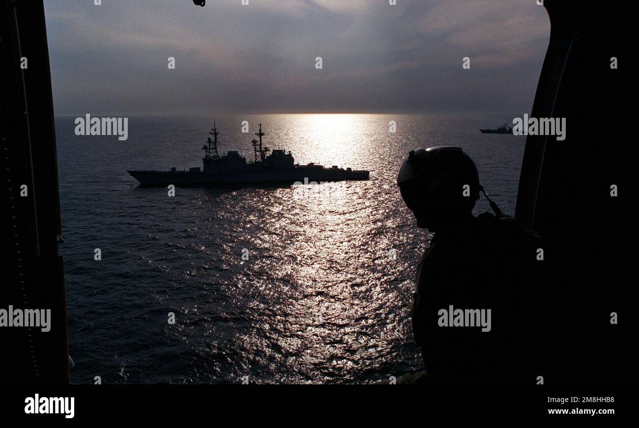 A crewman watches from the open door of his SH-3 Sea King as the helicopter passes by the destroyer USS DEYO (DD-989) during exercise BALTOPS '93. Subject Operation/Series: BALTOPS '93 Country: Baltic Sea Stock Photo
