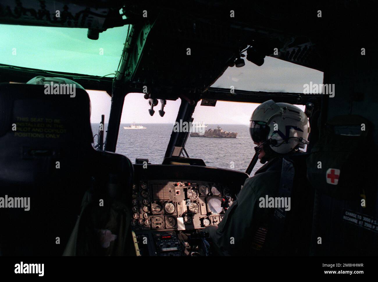 The pilot and copilot of an SH-3 Sea King fly their helicopter toward a formation of ships during exercise BALTOPS '93. Subject Operation/Series: BALTOPS '93 Country: Baltic Sea Stock Photo