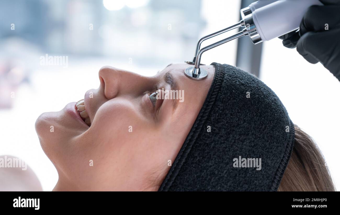 Young caucasian woman on microcurrent therapy procedure. Beautician's office. Stock Photo