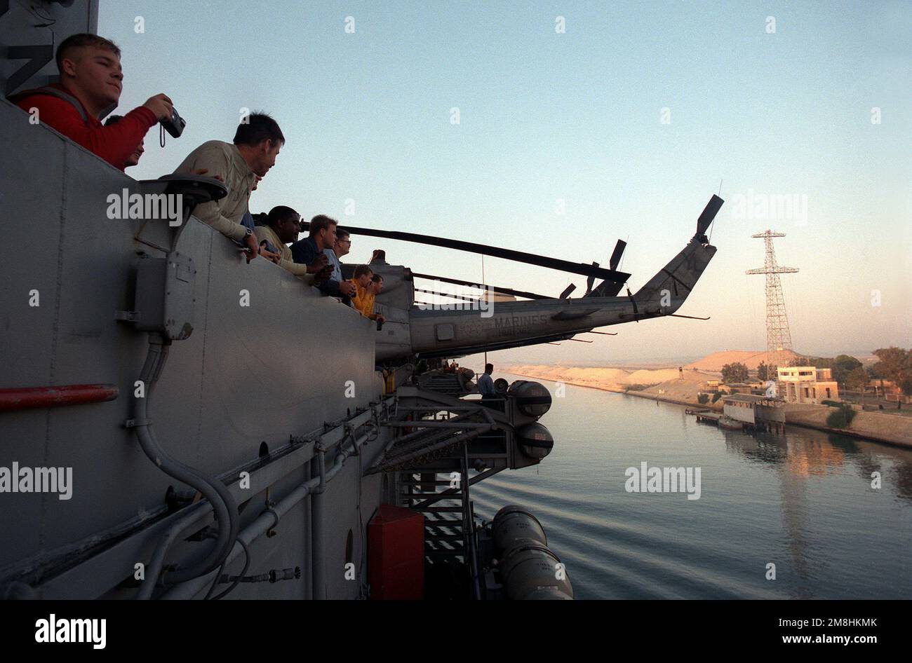Crew members watch from the railing aboard the nuclear-powered aircraft ...