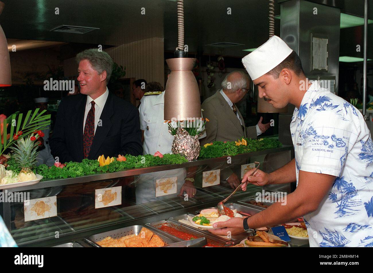 President William Jefferson Clinton greets a mess management specialist as he stands in the serving line of the enlisted galley with Adm. Charles R. Larson, commander-in-chief, U.S. Pacific Command, and Secretary of Defense Les Aspin. Clinton is in Hawaii to visit area military installations. Base: Naval Station, Pearl Harbor State: Hawaii (HI) Country: United States Of America (USA) Stock Photo