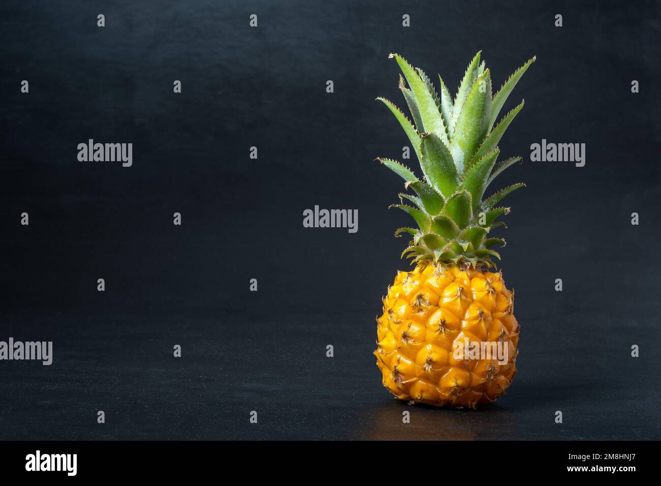 Ripe mini baby pineapple over dark background. Stock Photo
