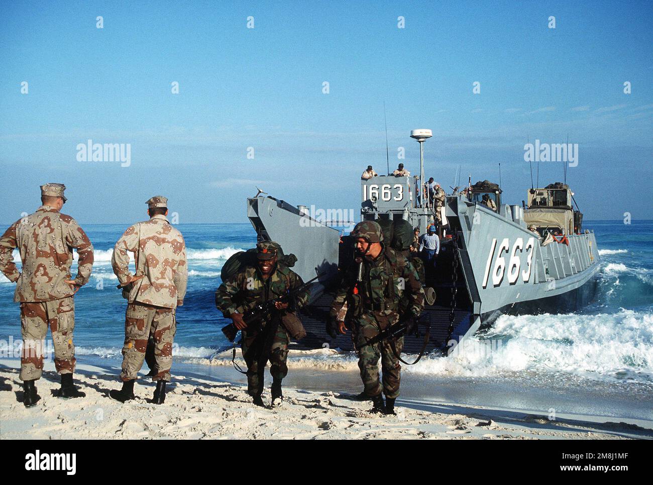 US Army members watch as US Navy Seabees from Amphibious Construction Battalion 2, Norfolk, Virginia, armed with M16 rifles and M60 machine guns, arrive on shore from a utility landing craft (LCU 1663) to a beach in Egypt during Exercise BRIGHT STAR '94. Subject Operation/Series: BRIGHT STAR '94 Country: Egypt (EGY) Stock Photo