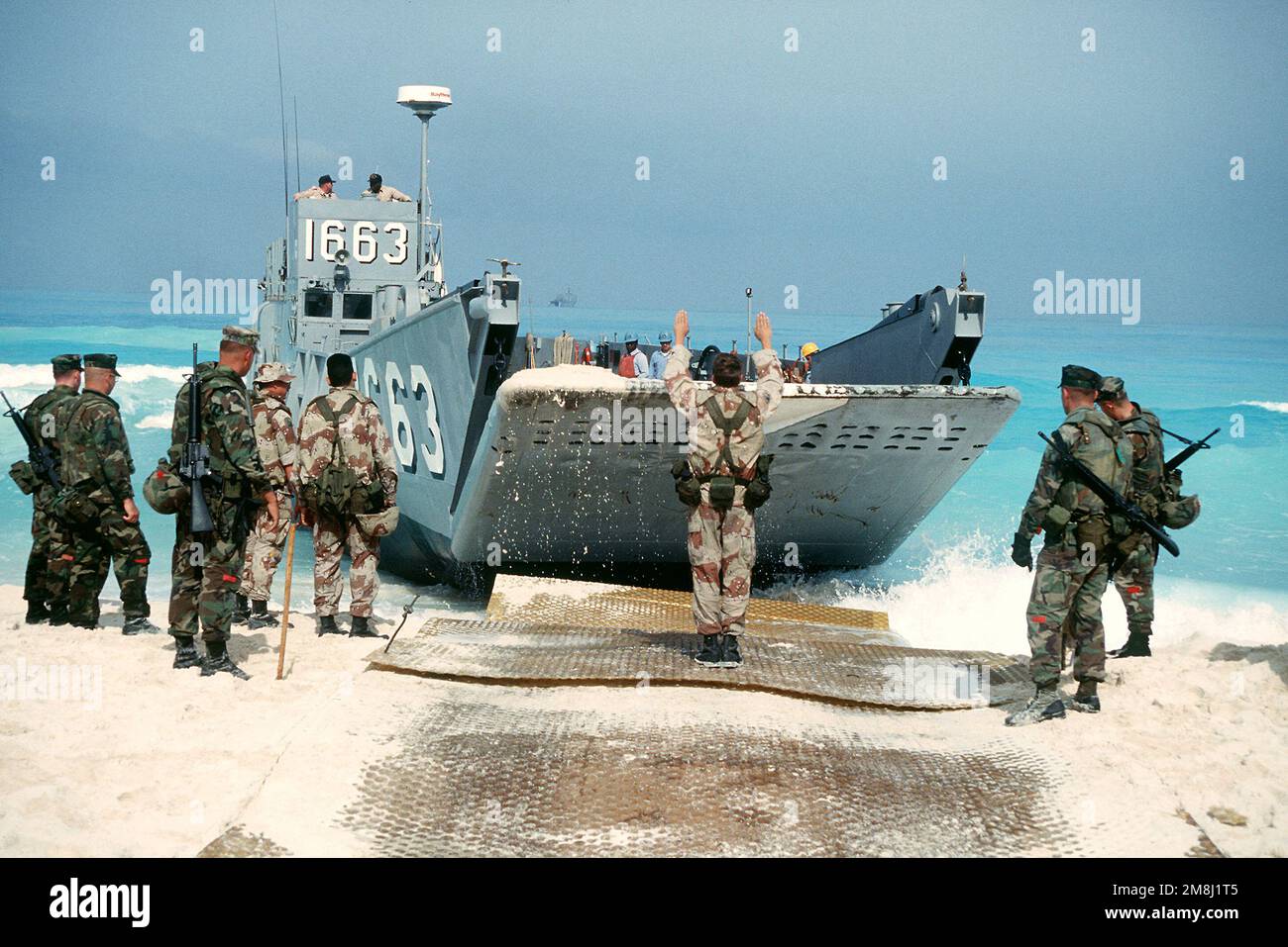 A US Army soldier signals as a utility landing craft (LCU 1663) prepares to depart a beach in Egypt after dropping off a group of US Navy Seabees from Amphibious Construction Battalion 2, armed with M16 rifles, during Exercise BRIGHT STAR '94. Subject Operation/Series: BRIGHT STAR '94 Country: Egypt (EGY) Stock Photo
