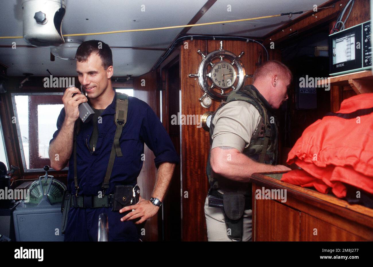 On the bridge of the Haitian-bound merchant vessel BLACK EAGLE, LTJG Craig Bowen, the assistant boarding officer from the training frigate USS AINSWORTH (FFT-1090) keeps in constant communication with the warship. To his left, MASTER CHIEF Boiler Technician (BTCM) George Cohn checks the ships radar and radio compartment during the 100th boarding of a Haitian-bound ship as part of Operation Support Democracy, the United Nations embargo on the flow of arms and fuel into Haiti. Subject Operation/Series: SUPPORT DEMOCRACY Country: Caribbean Sea Stock Photo