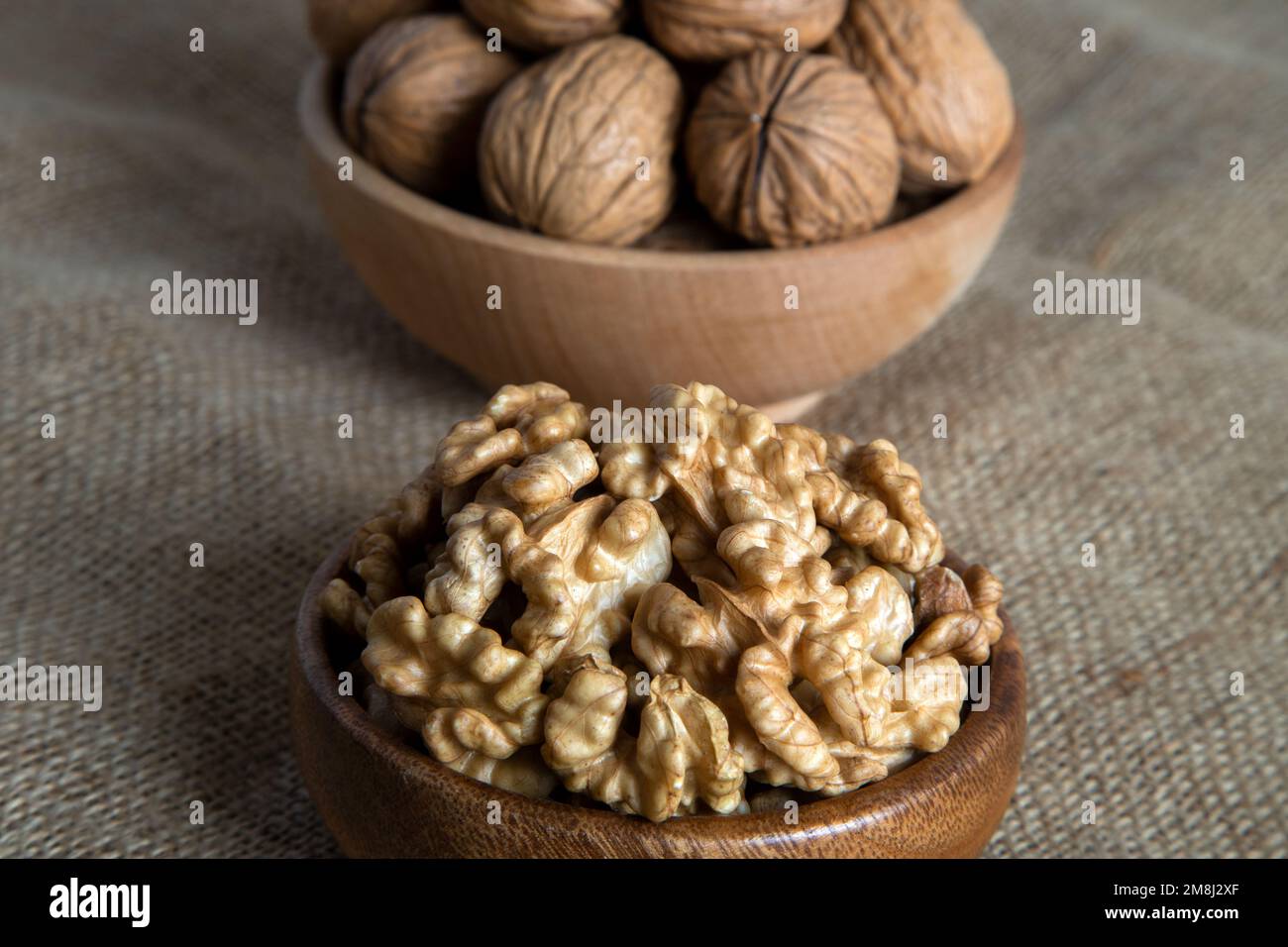 Peel walnuts and whole walnuts on burlap sack Stock Photo