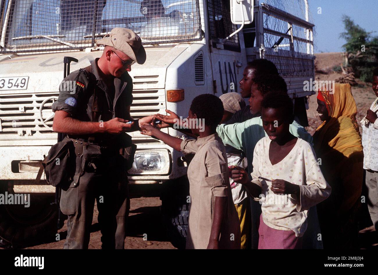 A German soldier hands out candy to Somali children in Belet Weyne. The soldier is part of the United Nations contingent supporting Operation CONTINUE HOPE. Subject Operation/Series: CONTINUE HOPE Base: Belet Uen Country: Somalia (SOM) Stock Photo