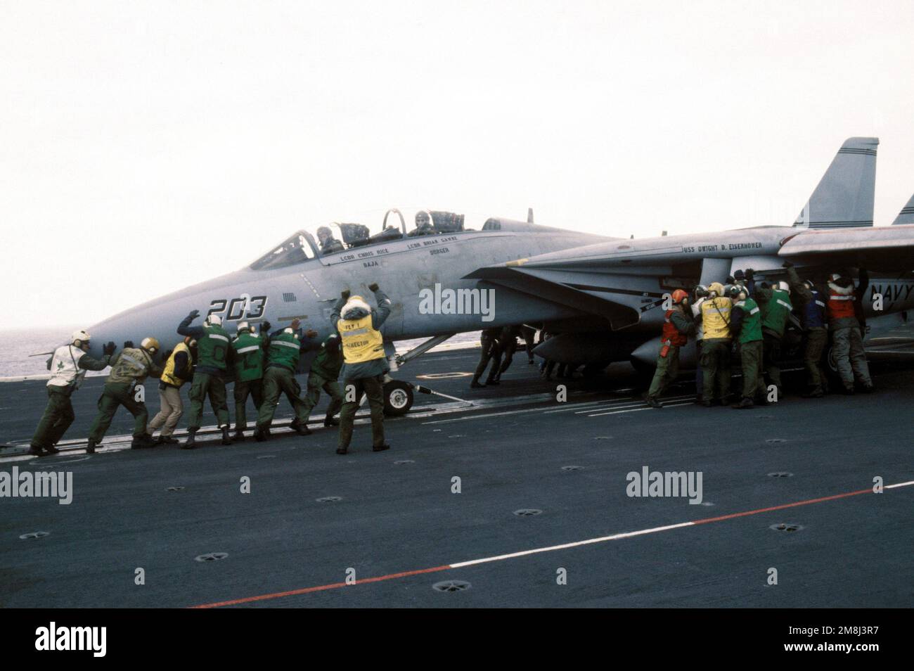 An F-14A Tomcat aircraft of Fighter Squadron Thirty Two (VF-32) is pushed back onto the catapult slot by flight deck personnel after overrunning the stop while preparing for launch from on board the nuclear-powered aircraft carrier USS DWIGHT D. EISENHOWER (CVN-69) during carrier qualifications off the Virginia Capes. Country: Atlantic Ocean (AOC) Stock Photo