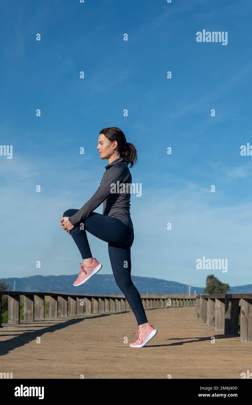 Leg stretching exercise fitness runner woman doing running warmup, hamstring muscles stretch