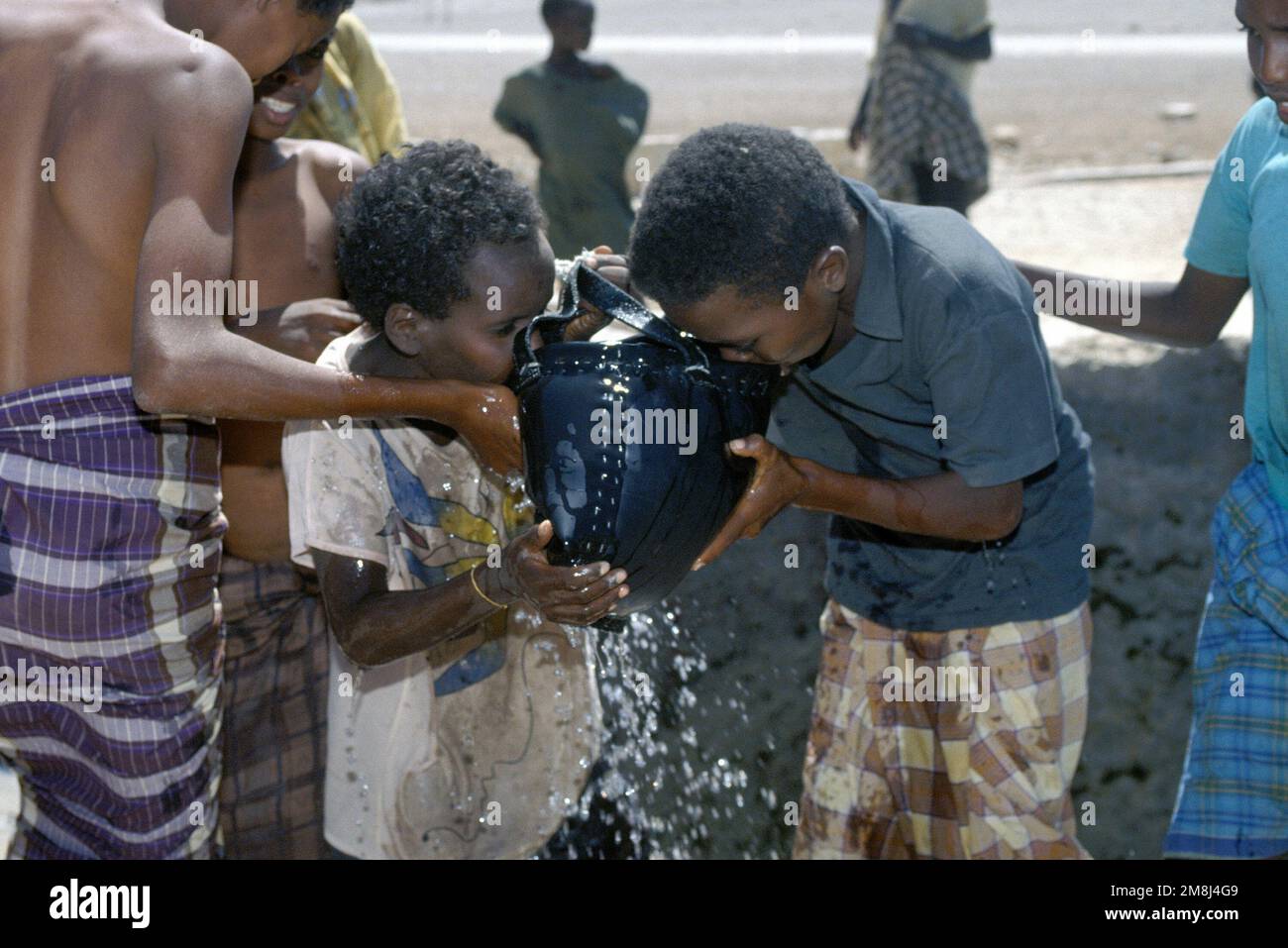 Somali children eagerly drink water drawn from an open well. Subject Operation/Series: UNOSOM II Base: Waajid Country: Somalia (SOM) Stock Photo