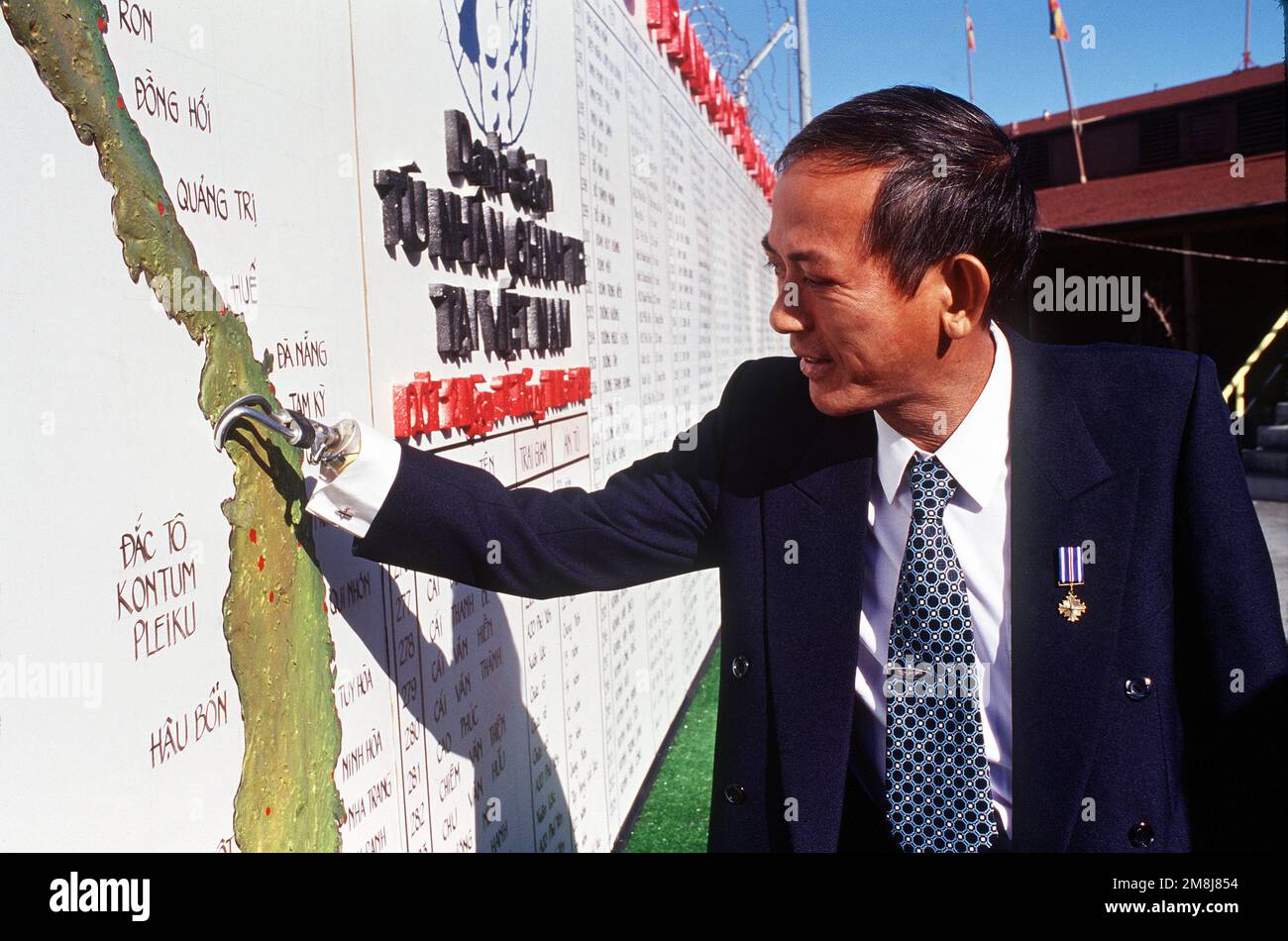 A former South Vietnamese Air Force helicopter pilot stands before a special memorial wall. MAJ Nquyen Quy An points, with his prosthetic hand, to a Vietnam map where he fought the communist north. An is wearing the Distinguished Flying Cross medal on his lapel he earned by risking his life to save four American soldiers in a sniper-filled jungle in Laos. Base: Travis Air Force Base State: California (CA) Country: United States Of America (USA) Stock Photo