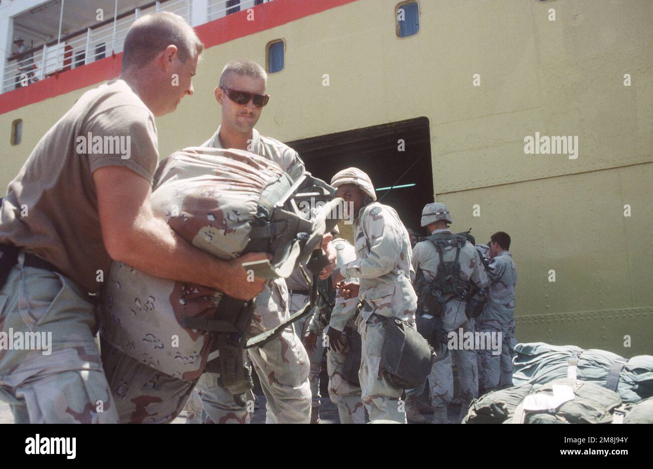 U.S. Army soldiers load baggage into cargo hole of the Military Sealift Command chartered vessel