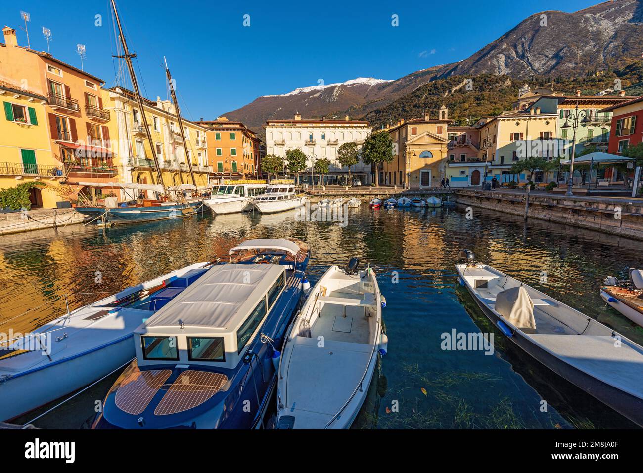Port of Malcesine village with small boats moored. Famous tourist resort on the coast of Lake Garda (Lago di Garda). Verona, Veneto, Italy, Europe. Stock Photo