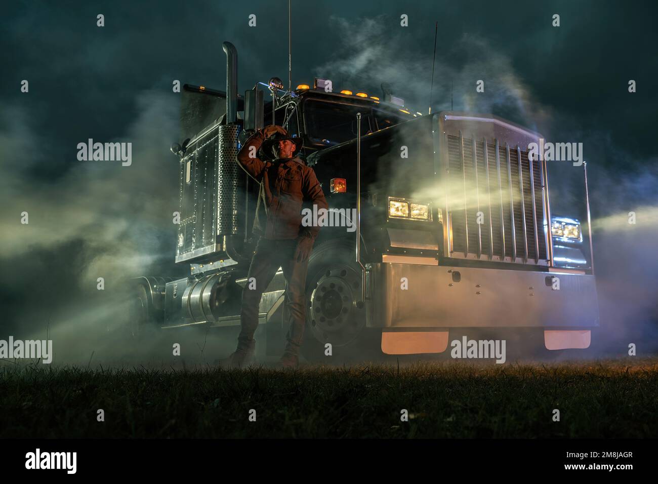 American Semi Truck Driver and His Vehicle During Foggy Night. Ground Shipping Transportation. Automotive Industry. Stock Photo