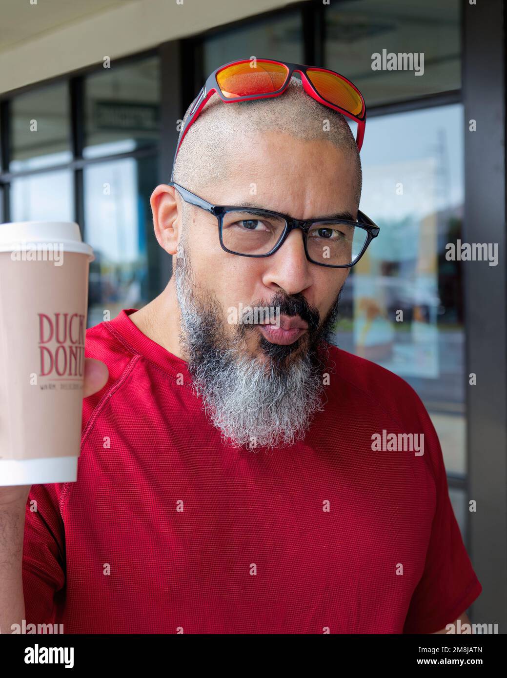 Outer Banks, NC - May 26, 2022 : Hispanic man holding Duck donuts cup. Person enjoying a beverage from Duck Donuts Franchise Stock Photo