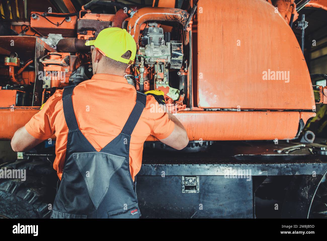 Excavator Mechanic Taking Closer Look Into the Machine Diesel Engine