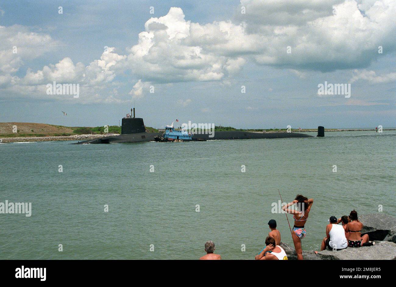 A port side view of the British nuclear-powered ballistic missile submarine HMS VANGUARD (SSBN-50) being assisted up the channel by a civilian tug boat. Base: Port Canaveral State: Florida (FL) Country: United States Of America (USA) Stock Photo