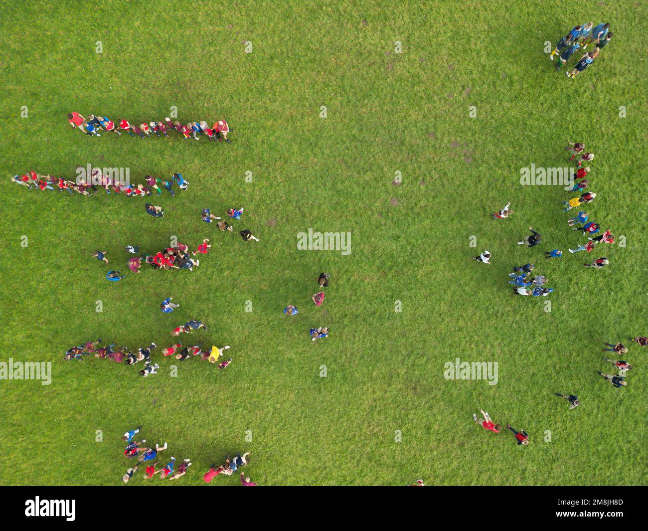 A bird's eye view of a group of kids playing on a green field Stock