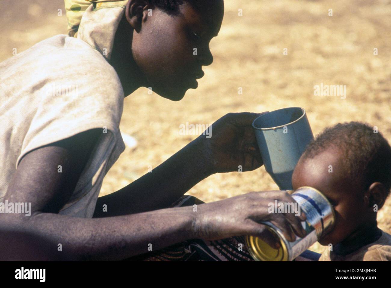 A Rwandan mother gives her child a drink of water. Rwandan refugees ...