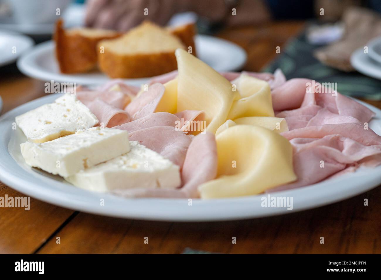 Brazilian breakfast concept with Minas cheese (queijo minas), ham and Prato cheese (queijo Prato) served with corn bread, under natural light, realist Stock Photo