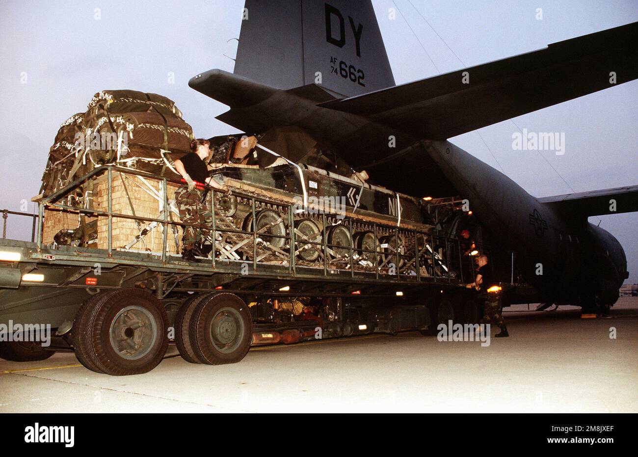 A medium shot of an Army tank being loaded onto a C130. Subject