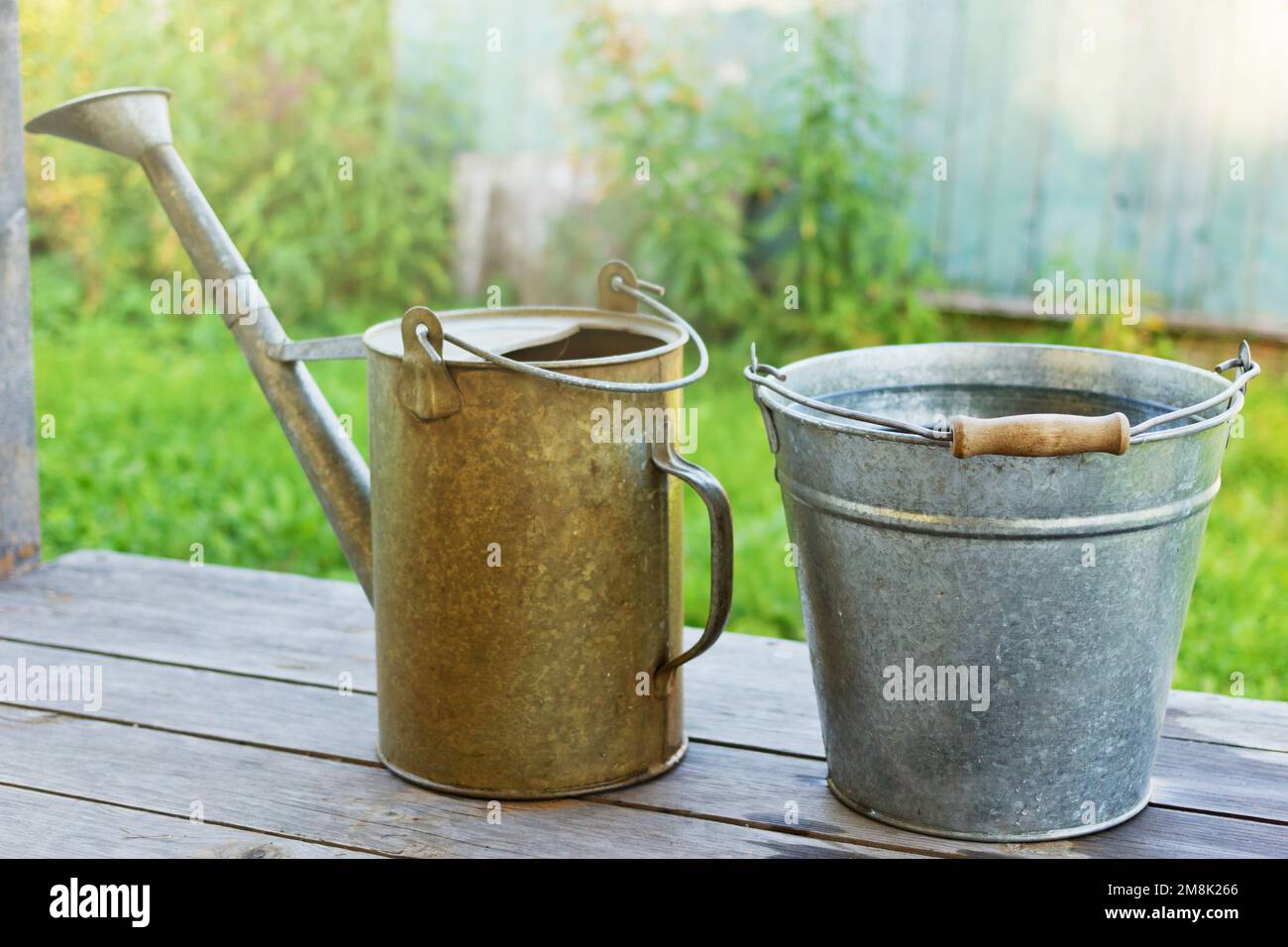 Metal bucket with water and watering-pot on the wooden porch Stock Photo
