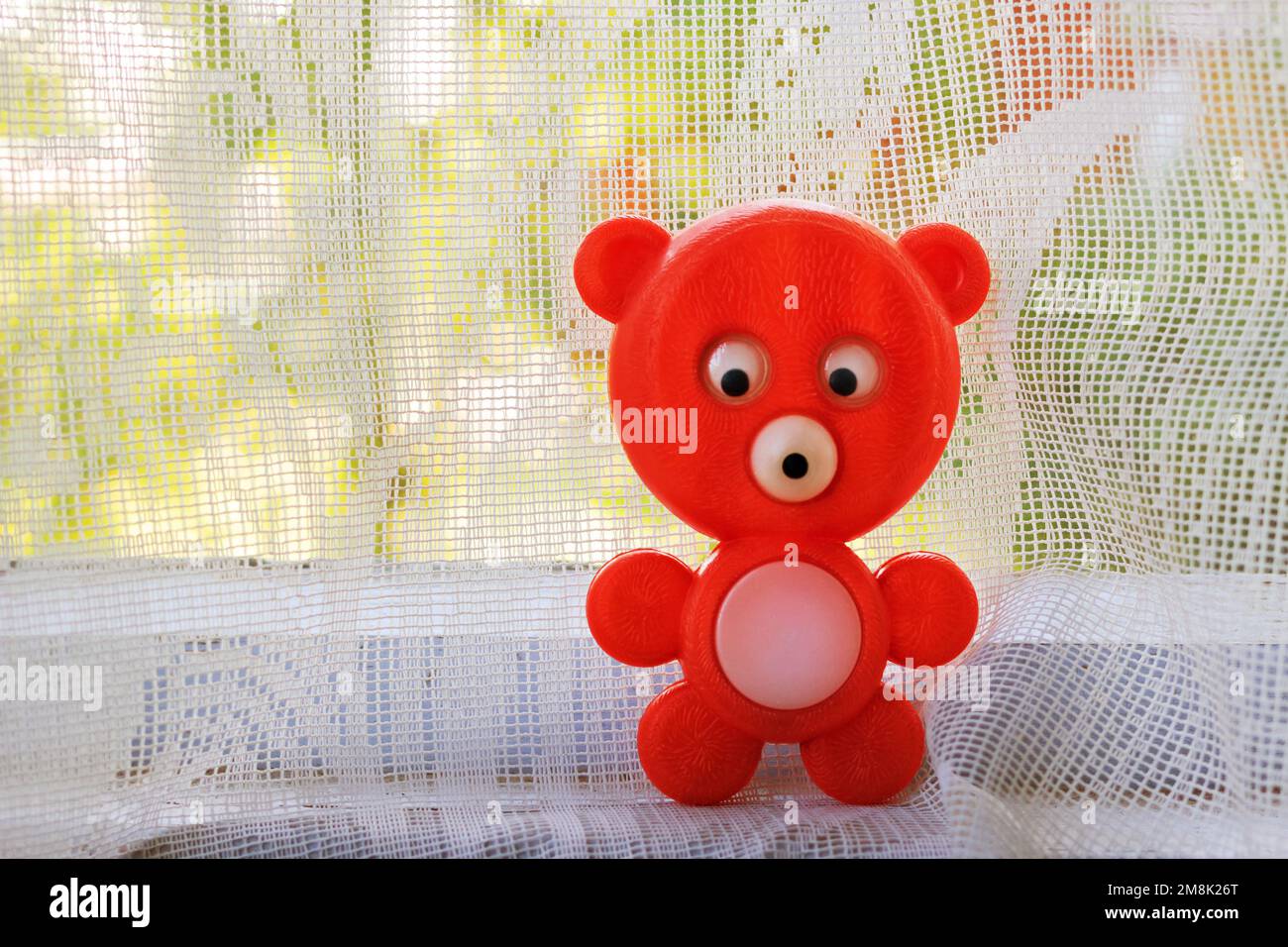 Old soviet plastic toy red bear on the inside window-still Stock Photo
