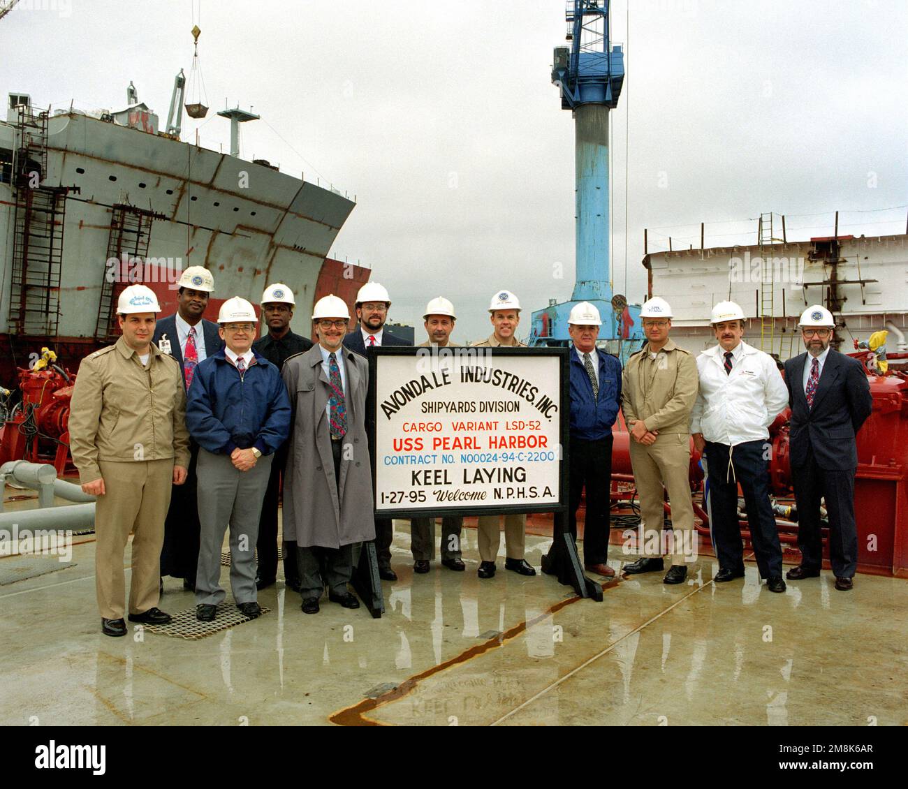 The official party at the keel laying of the dock landing ship Pearl Harbor (LSD-52). (L-R) LT. Frank Simei, Proj. Officer; H.J. Brown, Hull Mgr; A.J. Thibodeaux, Proj. Mgr; T.E. Johnson, Asst. Hull Mgr; Carey Agregaard, Asst. Program Mgr; James Roemer, CHIEF Engineer; Louis Duet, Asst. Configuration Mgr; CDR. James L. Jenkins, USN, Supervisor of Shipbuilding; Ronnie Clark, Lead Production Engineer; LCDR. Bill Salinas, USN, Project Officer; David Gordon, Program Mgr; Bernard P. Clark, Deputy Supervisor of Shipbuilding. Base: Avondale State: Louisiana (LA) Country: United States Of America (USA Stock Photo