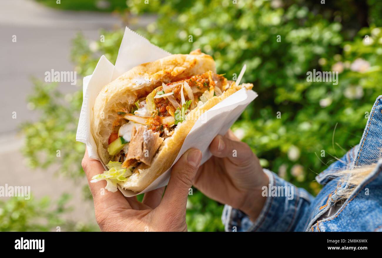 Woman holding a Doner Kebab (sandwich) in Germany famous kebab fast food snack in flatbread. Stock Photo