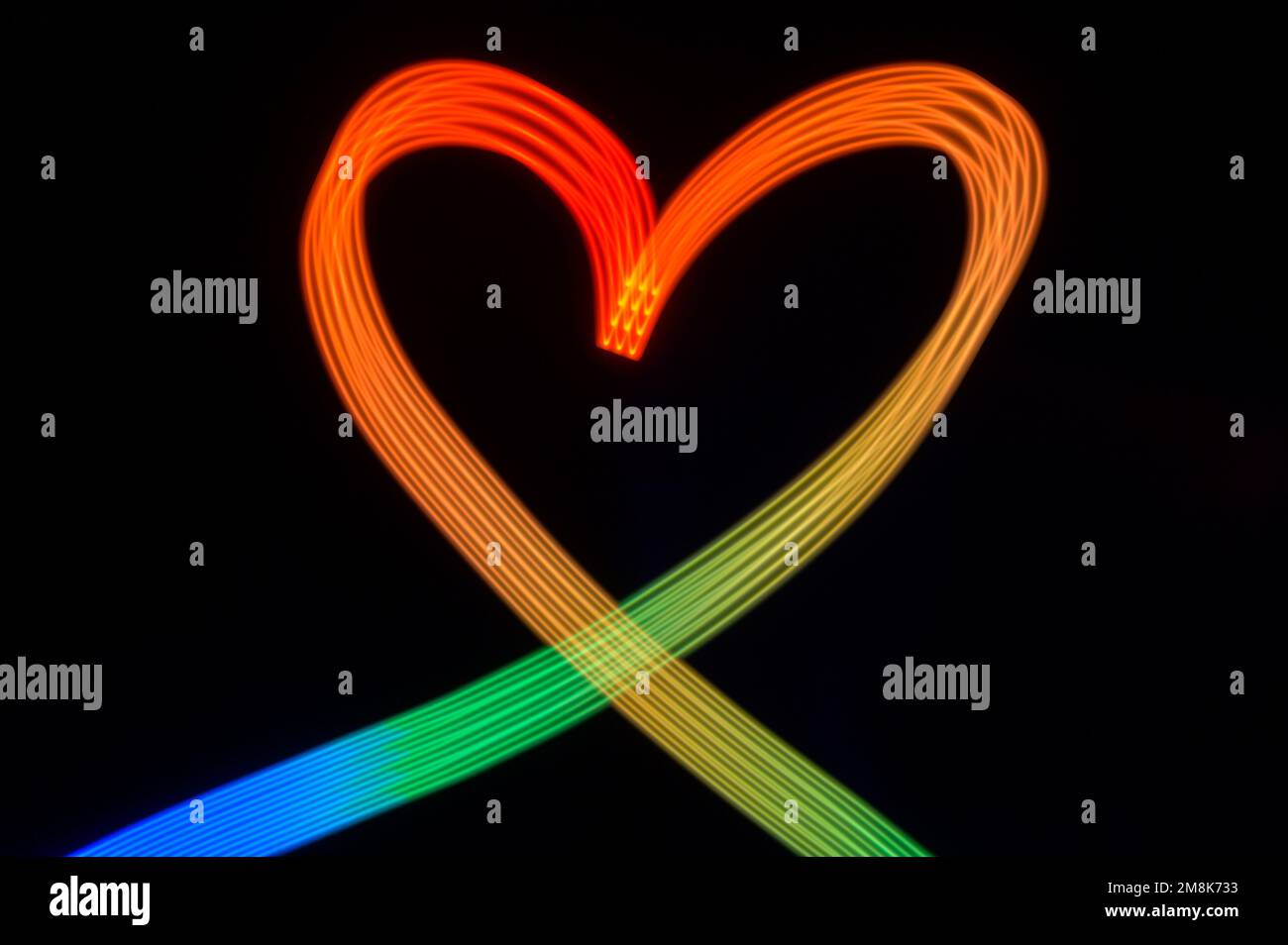 Rainbow colored light painted heart on black background Stock Photo