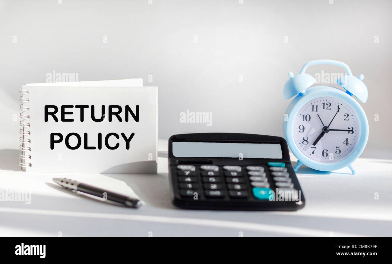 RETURN POLICY text written on notepad, next to calculator, clock and pen on white background Stock Photo
