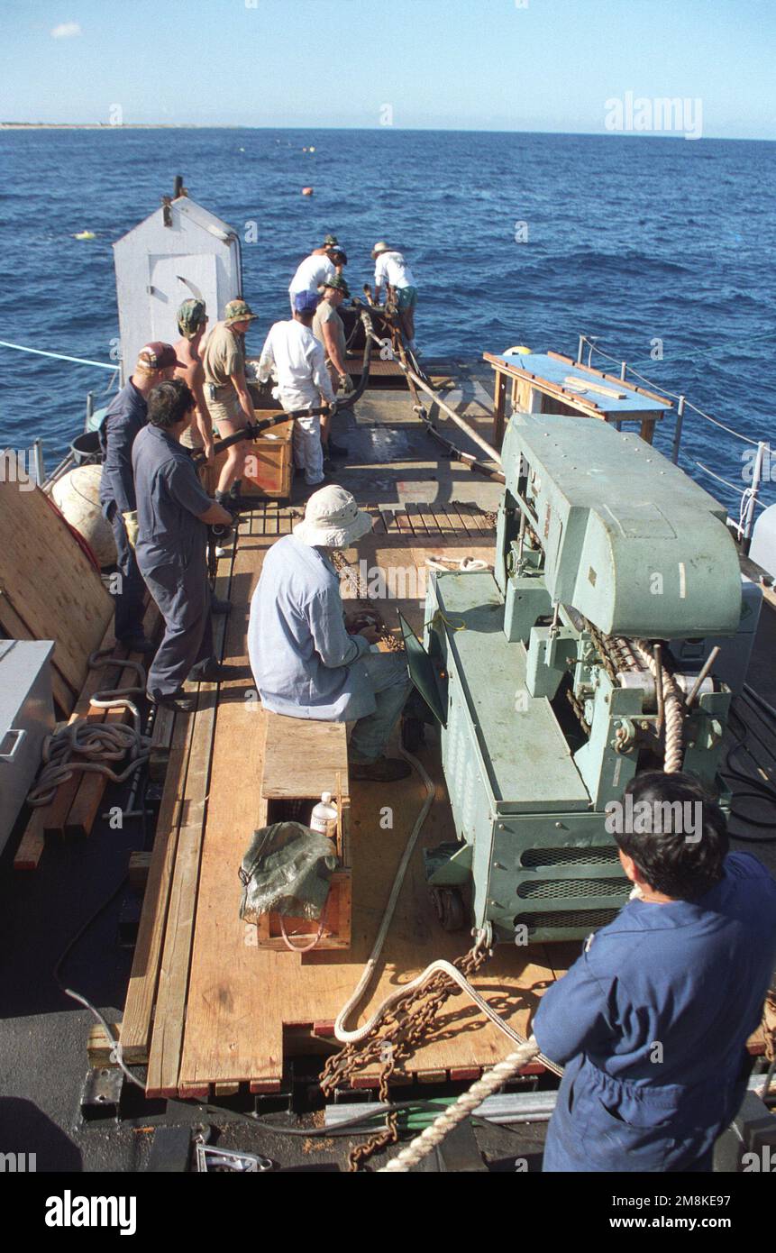 Members of Underwater Construction Team Two (UCT-2) and personnel of the Pacific Missile Range Facility work on replacing cable and splicing in a new section from the Navy service craft RED BARON (a former torpedo retriever boat) off Kauai, Hawaii. (Exact date unknown). Country: Pacific Ocean (POC) Stock Photo