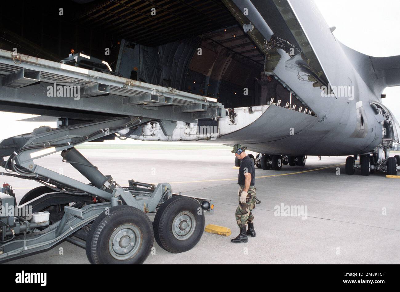 TSGT Adam J. Knight, cargo supervisor, 72nd Aerial Port Squadron, Tinker AFB, OK, keeps watch as a 20,000 lb. capacity K-Loader inches up to the safety chock he placed at the rear of the aft cargo ramp of a C-5B Galaxy from the 60th and 349th Air Mobility Wings, Travis Air Force Base, California before off loading personnel and equipment. Air Force members will practice their jobs with wartime scenarios and conditions during the Operational Readiness Inspection (ORI), testing a unit's ability to operate in a simulated wartime environment. Subject Operation/Series: CRISIS REACH 95-02NORTHERN PI Stock Photo