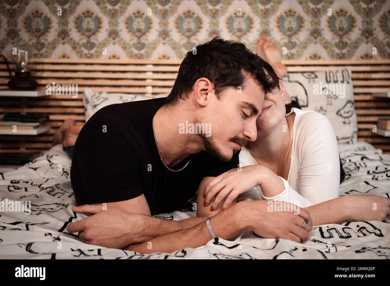Happy couple is lying on the bed and cuddling. Young romantic lovers intimate moments. Intimacy and love relationship concept Stock Photo