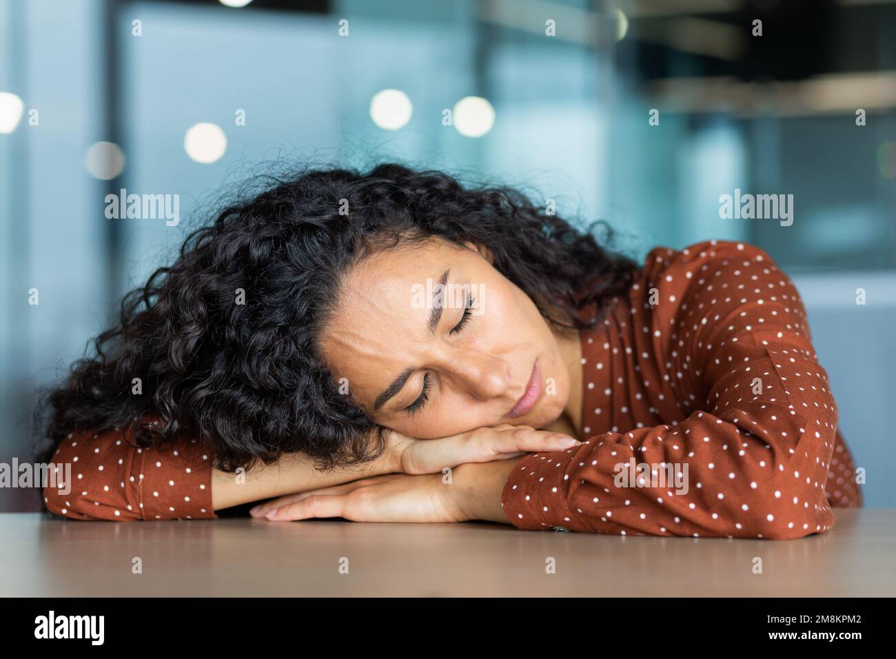 Beautiful tired hispanic woman sleeping on desk, close-up business woman with closed eyes napping inside office near laptop. Stock Photo
