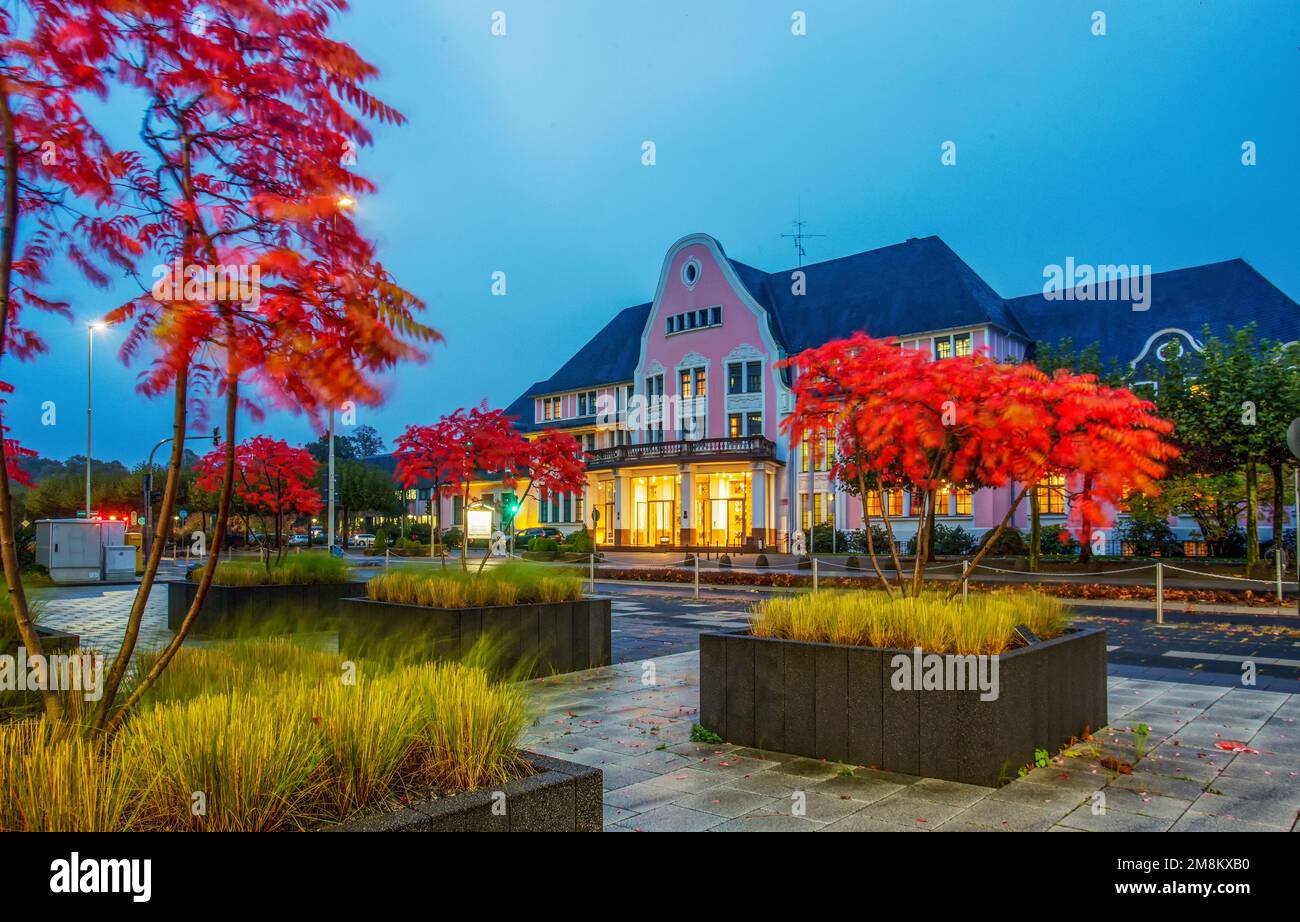 Awe garden in potted plants with autumn leaf color , red leaves,  next to factory in Leverkusen and old building in distance (leaves blurred from wind Stock Photo