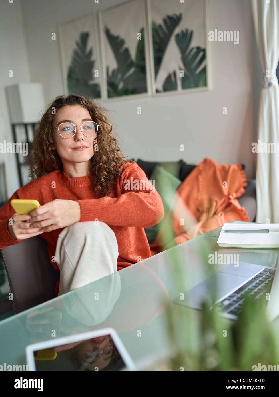 Young woman using phone studying or remote working at home. Vertical Stock Photo