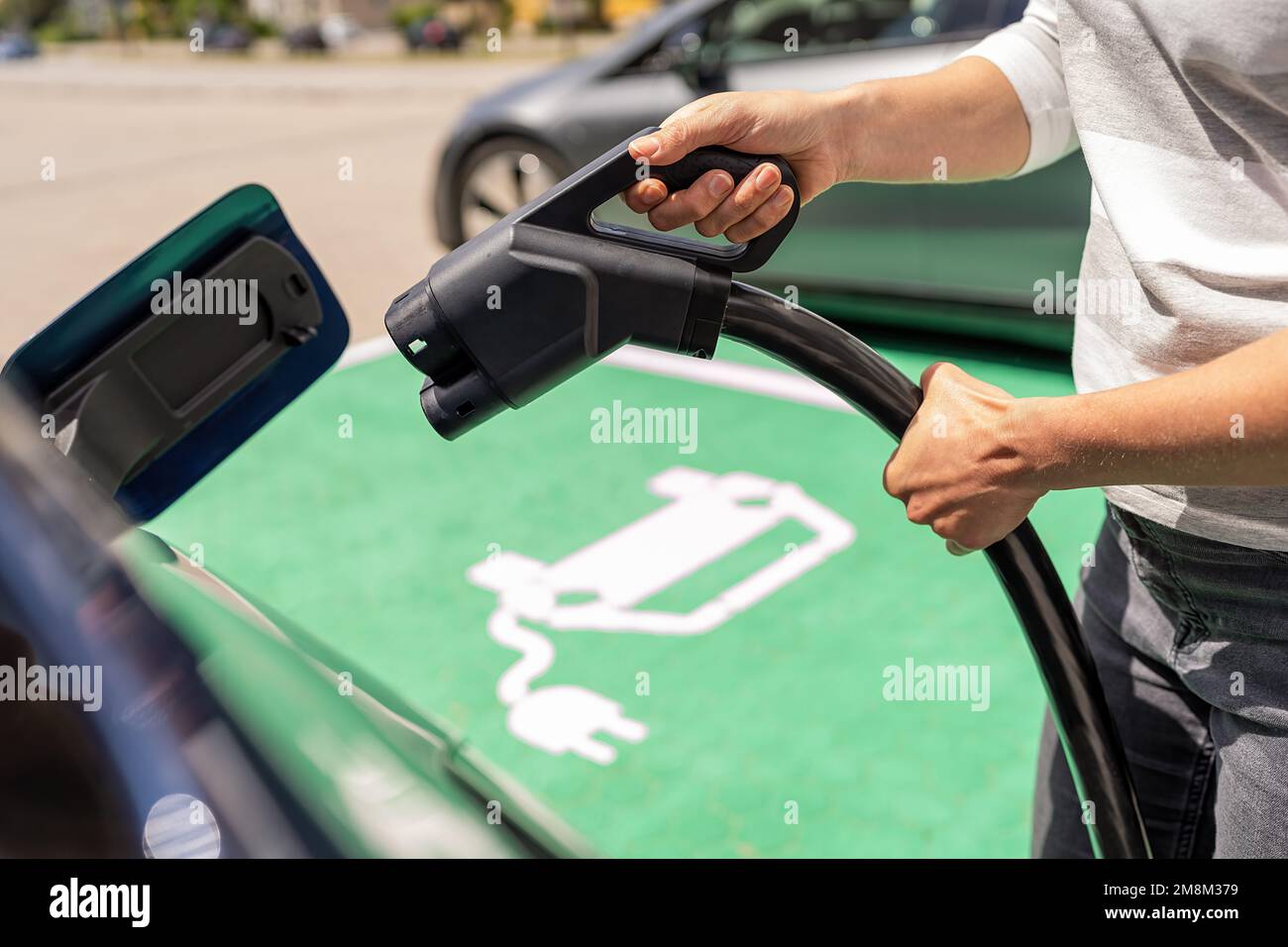 Hand inserting a DC CCS2 EV charging plug into electric car socket at