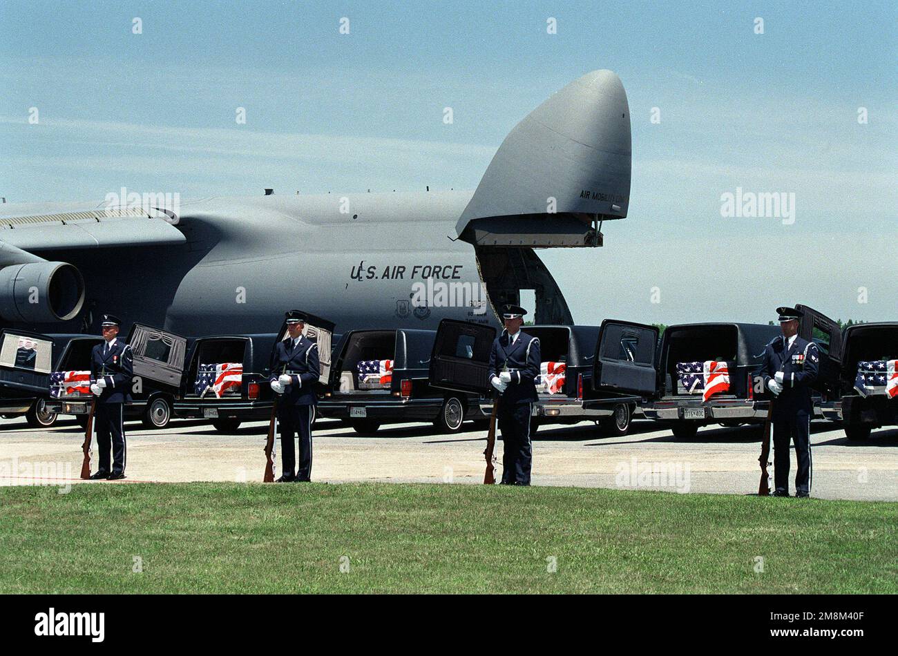 Against a background of a 60th Air Mobility Wing C-5 Galaxy aircraft, hearses bear flag draped caskets containing the remains of U.S. military service members killed in the Dhahran, Saudi Arabia bombing, at Dover Air Force Base, Delaware on June 27, 1996. Base: Dover Air Force Base State: Delaware (DE) Country: United States Of America (USA) Stock Photo