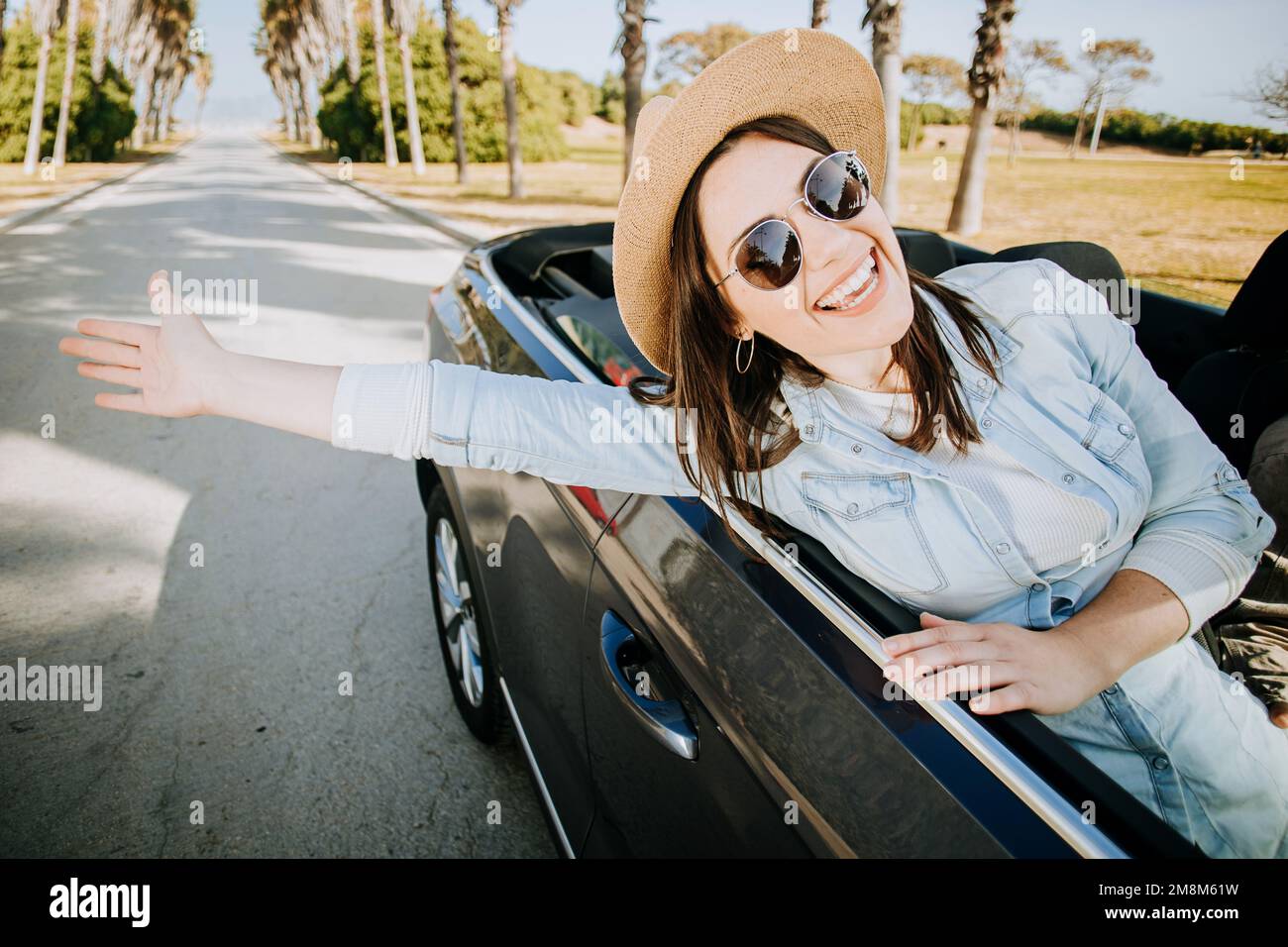 Happy young woman enjoying freedom on travel trip by cabriolet car Stock Photo