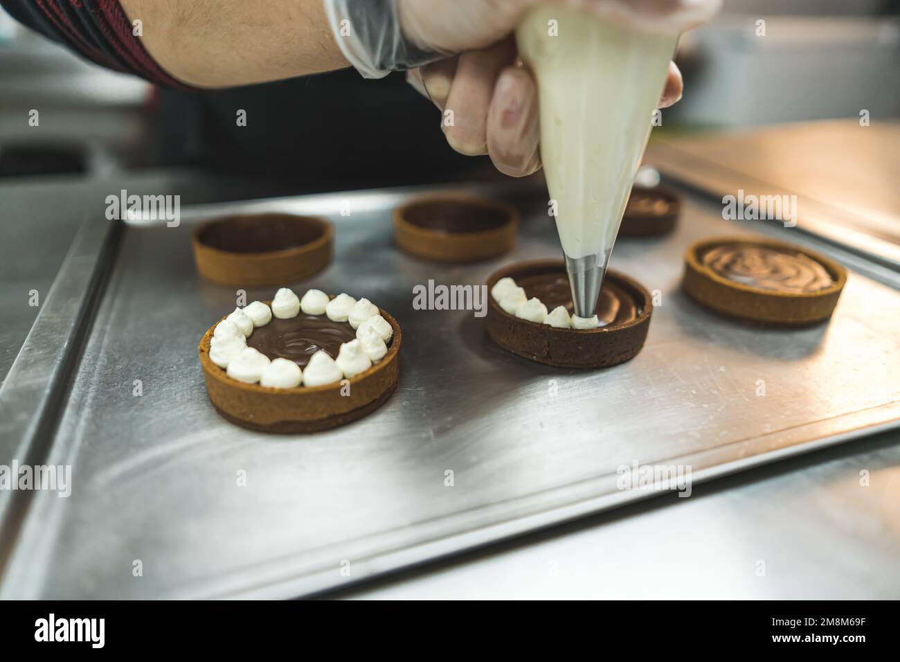 baker piping cream on chocolate cakes at the bakery, dessert concept. High quality photo Stock Photo